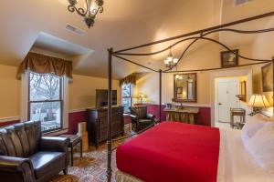 um quarto com uma cama grande e uma colcha vermelha em Steele Mansion Inn & Gathering Hub em Painesville