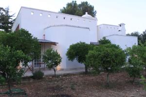 ein weißes Gebäude mit Bäumen davor in der Unterkunft Il Boschetto in San Vito dei Normanni