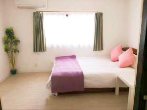 Schlafzimmer mit einem Bett mit rosa Kissen und einem Fenster in der Unterkunft 2 floors japanese style, direct to KIX, 10mins train to Namba, 5mins walk to stn , 2-6ppl in Osaka
