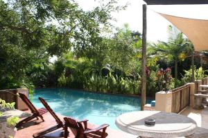 una piscina con due sedie e un tavolo di Villa Royal Palm a Komatipoort