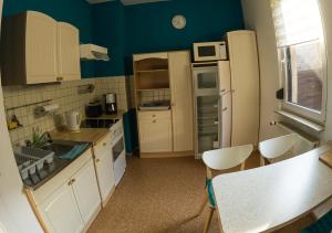 a small kitchen with blue walls and white cabinets at Ferienwohnung Wanderurlaub Thüringen in Schmalkalden