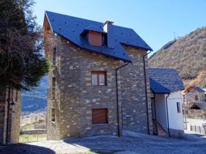 een stenen huis met een blauw dak bij Apartamento Bachimala in Huesca