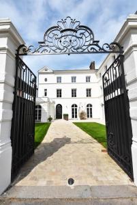 une entrée à une maison blanche avec un portail dans l'établissement Manoir de l'évêché, à Lisieux