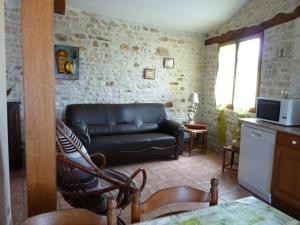 a living room with a leather couch and a kitchen at Gîtes Chez Belliveau in Meursac