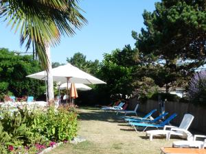 a group of chairs and an umbrella in a yard at Gîtes Chez Belliveau in Meursac