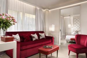 Ponte Vecchio Suites & Spa في فلورنسا: غرفة معيشة مع أريكة حمراء وسرير