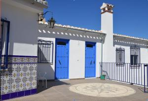 un edificio blanco con puertas azules y azulejos en él en Casa Rural - Santo Domingo Rural, en Archidona