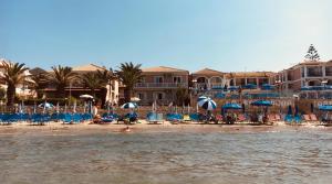 a beach with chairs and umbrellas and people in the water at Roula Kotsonis Superior Apartment in Argassi