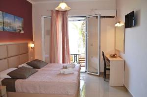 a bedroom with a bed and a desk and a window at Roula Kotsonis Superior Apartment in Argassi