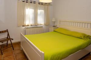 Un dormitorio con una cama verde con una silla y una ventana en Cal Roig - Pedraforca, en Saldes 30 fotos más