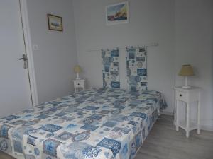 a bedroom with a bed with a blue and white comforter at Appartement Kervoyal in Kervoyal