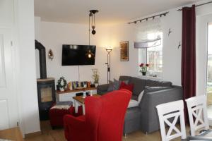 Reethaus Casa Baltica في بورغيريندي-ريثفيش: غرفة معيشة مع أريكة رمادية وكراسي حمراء