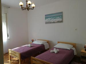 Duas camas num quarto com lençóis roxos e um lustre em Apartment Mario em Split