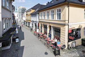 Bergen's Best Location في بيرغِن: شارع فيه مجموعة طاولات وكراسي على مبنى