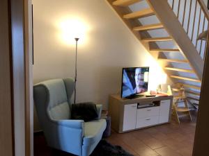 ein Wohnzimmer mit einem Stuhl, einem TV und einer Treppe in der Unterkunft MeerZeit in Zingst