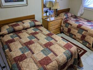 a bedroom with two beds and a dresser with a quilt at Oakview Hotel in Wildwood