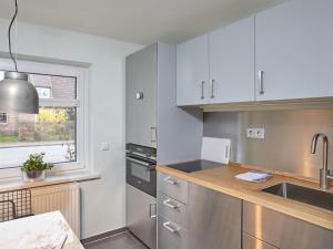 a kitchen with white cabinets and a sink and a window at Düne 6 in Sankt Peter-Ording