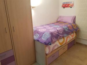 Dormitorio pequeño con cama pequeña con sábanas moradas en piso turístico, en Tarragona