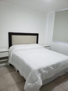 ein Schlafzimmer mit einem weißen Bett und zwei Nachttischen in der Unterkunft Departamento Centrico in Villa María