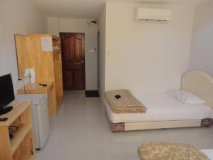 a small room with a bed and a desk with a computer at Pupha Mansion in Chaweng Noi Beach