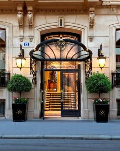 a door to a building with two potted plants at Hôtel San Régis in Paris