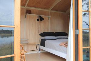 Cama en habitación pequeña con ventana en The Bird Hide - rustic luxury by the water en Dunedin