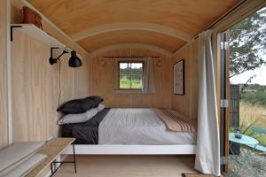 Cama en habitación pequeña con ventana en The Bird Hide - rustic luxury by the water, en Dunedin