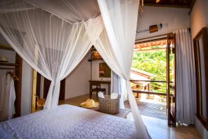a bedroom with a bed with white curtains and a window at Biribandos Rooms by Trancoso House in Trancoso +148 photos