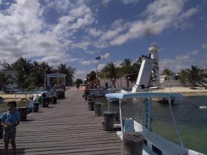 a boy standing on a dock next to a boat at Los Balcones Puerto Morelos in Puerto Morelos