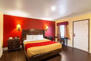 Econo Lodge Long Beach I-405 في لونغ بيتش: غرفة فندق بسرير وجدار احمر