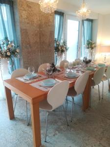 un lungo tavolo in legno con sedie bianche intorno di Angel's Nest Apartment a Komenda
