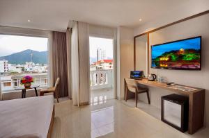 a hotel room with a bed and a desk and a tv at For You Hotel in Nha Trang