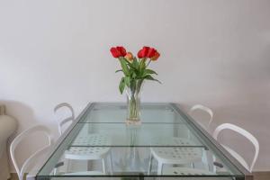 a glass table with a vase of red roses on it at Casa Grazia Letojanni Centro in Letojanni