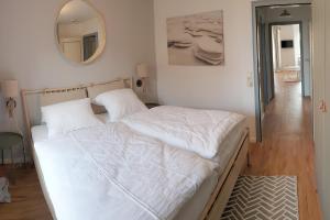 ein weißes Bett in einem Zimmer mit Spiegel in der Unterkunft Ferienwohnung *Windstille* in Wittdün