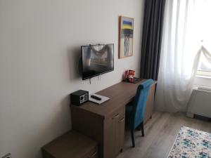 Habitación con escritorio, TV y silla. en Atlas City Center Hotel en Prilep