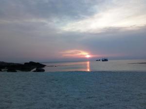 a sunset on the beach with a boat in the water at Nangyuan Island Dive Resort in Ko Tao