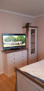 a bedroom with a flat screen tv on a dresser at Ferienwohnung Steffens Scharbeutz in Scharbeutz