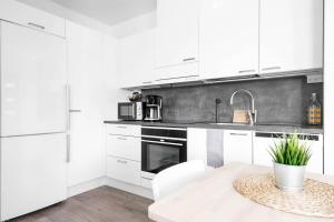 a kitchen with white cabinets and a sink and a table at Vihtakatu Apartments in Järvenpää
