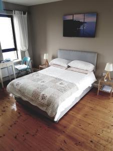 a bedroom with a large white bed with a wooden floor at Our View in Doolin