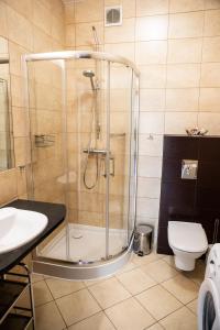ein Bad mit einer Dusche, einem WC und einem Waschbecken in der Unterkunft OK Apartament Uzdrowiskowa in Świnoujście