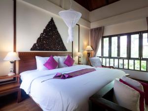 a bedroom with a large white bed with purple pillows at Royal Lanta Resort & Spa in Ko Lanta