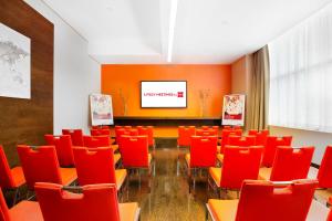 a conference room with red chairs and a screen at Ibis Al Rigga in Dubai