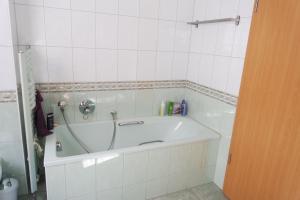 a bath tub in a white tiled bathroom at Ferienwohnung "Hedwig" in Bad Saarow +16 photos