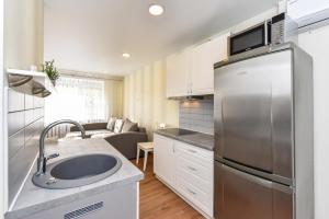 a kitchen with a sink and a stainless steel refrigerator at Baltieji Senamiesčio Apartamentai prie Aqua Parko in Druskininkai