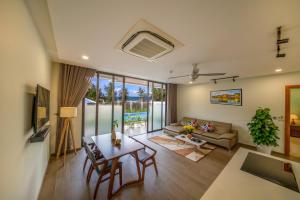 uma sala de estar com uma mesa e um sofá em Beach Haven Suites Hội An Apartment em Hoi An