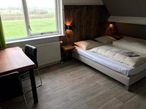 a bedroom with a bed and a table and two windows at Hofstede Elzenoord in Vrouwenpolder