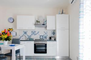 Una cocina blanca con gabinetes blancos y una mesa. en BENVENUTI AL SUD, en Castellammare del Golfo 33 fotos más