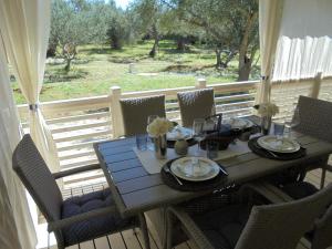 a table and chairs on a porch with a view of a yard at Mobilna kućica Luka in Sveti Filip i Jakov