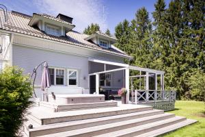 une maison blanche avec une terrasse couverte et des escaliers dans l'établissement Villa Satulinna, à Kotka