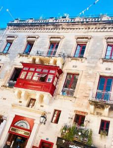 een gebouw met een rood balkon aan de zijkant bij Luciano Valletta Boutique in Valletta